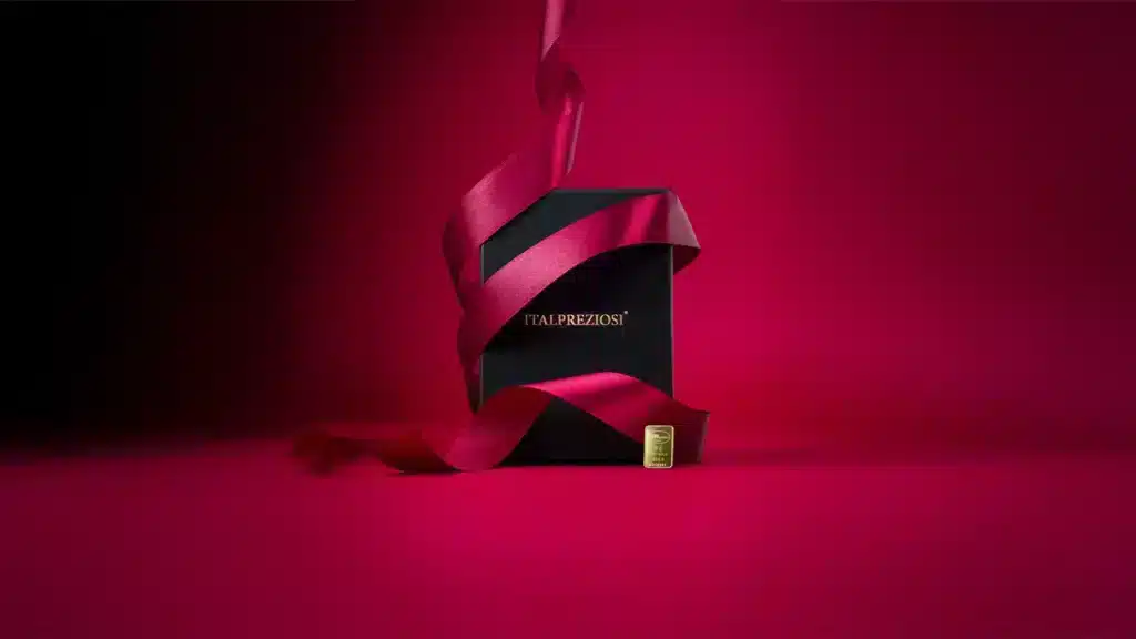 Il Lingotto Argento 10 Oz è presentato in una scatola nera Italpreziosi, avvolta da un nastro di raso rosso su sfondo rosso, che ne sottolinea la presentazione lussuosa ed elegante.