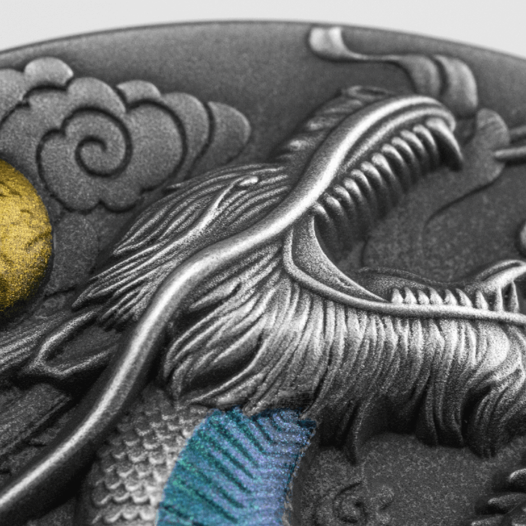 Close-up of the Year of the Dragon 2024 CFA Francs, showcasing a detailed embossed dragon with intricate scales, metallic gold and blue accents, and swirling gray background patterns.
